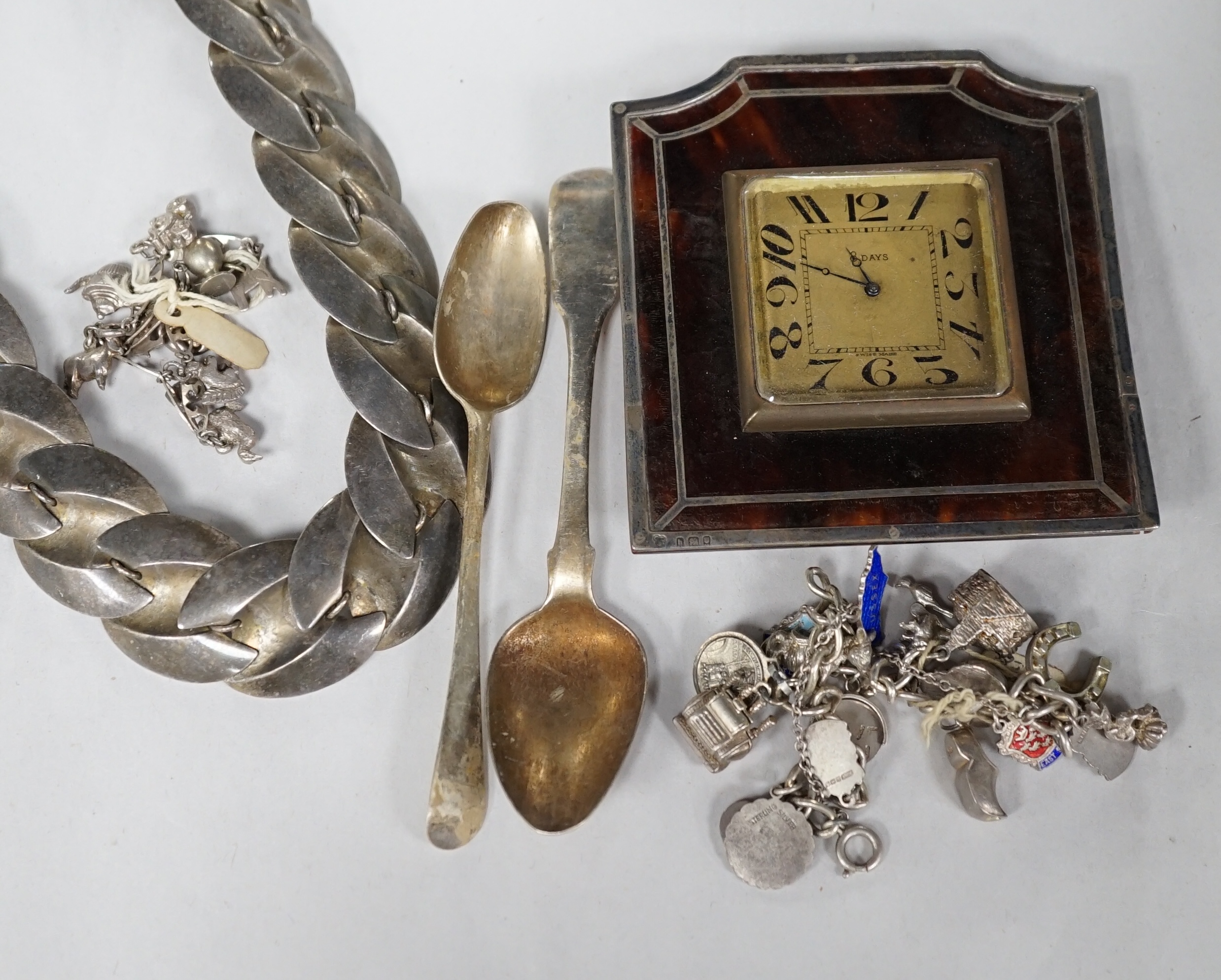 A silver charm bracelet, hung with assorted charms, some hallmarked, one other white metal charm bracelet, a stylish white metal necklace, two silver teaspoons and a George V silver and tortoiseshell mounted timepiece, L